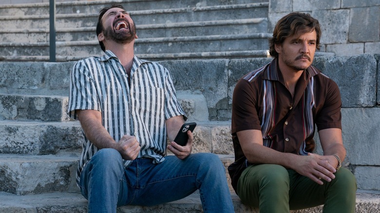 Nicholas Cage and Pedro Pascal sit on stairs