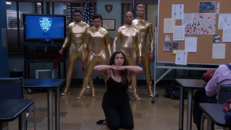 Gina Linetti dancing with four men in gold morph suits