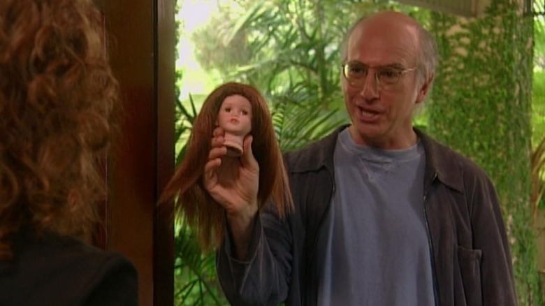 Larry David holding a doll's head