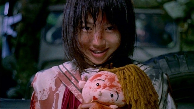 A manic looking child with a bloodied doll