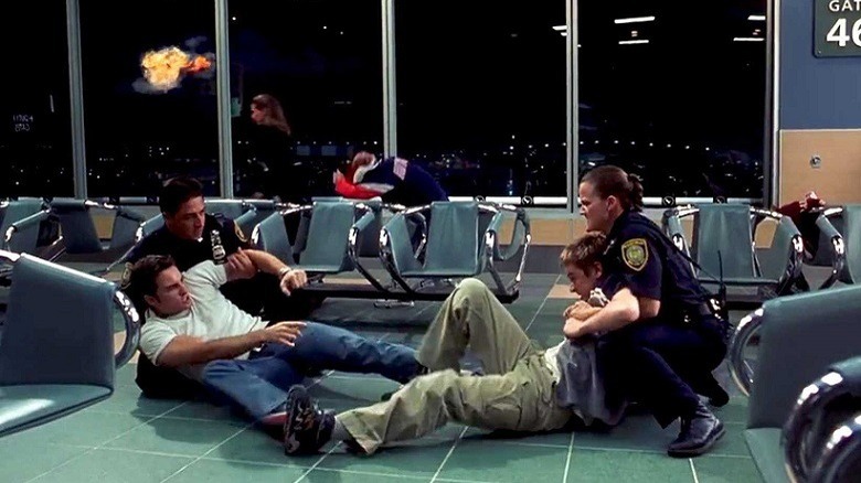 A fight ensures in an airport terminal as, outside, a plane explodes