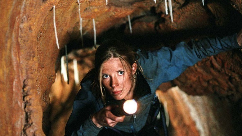 Our heroine crawls through a cave with a torch