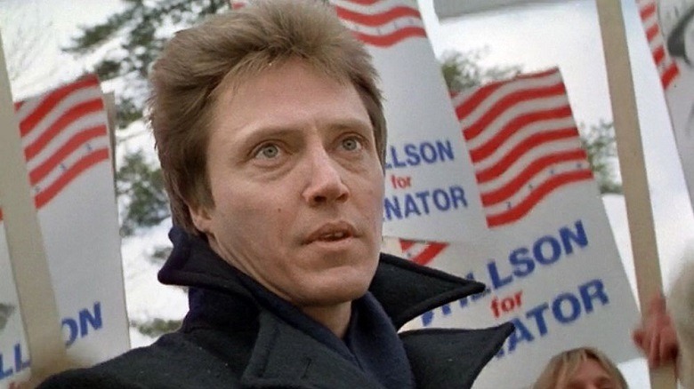 Christopher Walken in front of banners