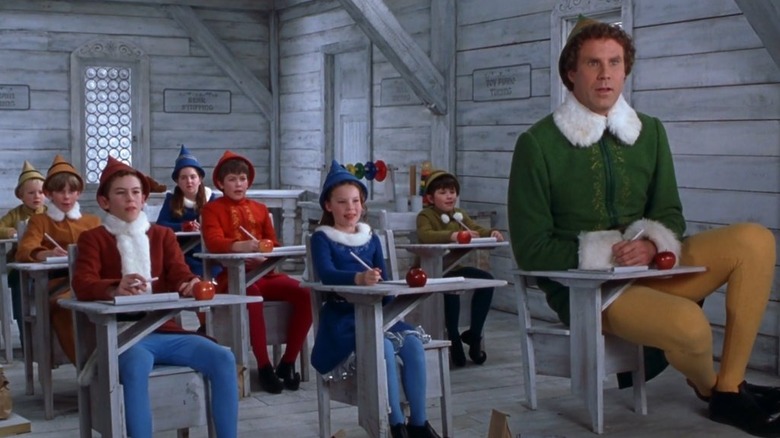 Will Ferrell as Buddy the Elf sitting at a desk with his elf classmates in Elf.