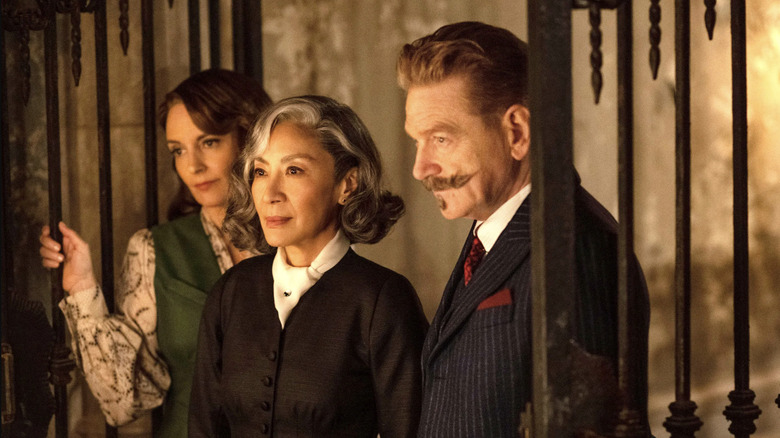 Ariadne Oliver, Joyce Reynolds, and Hercule Poirot standing together in A Haunting in Venice