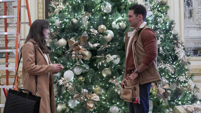 Jessica and Nick standing by giant Christmas tree in Christmas at the Plaza