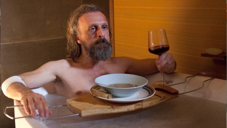 man drinks wine in bath in Borgman