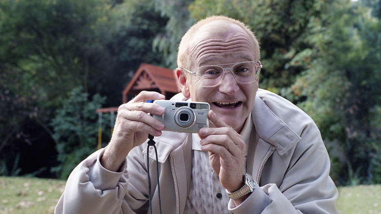 Robin Williams holding a camera and smiling in One Hour Photo