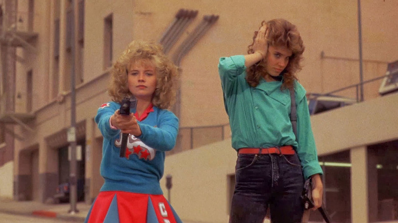 Cheerleader aims gun while friend covers ear