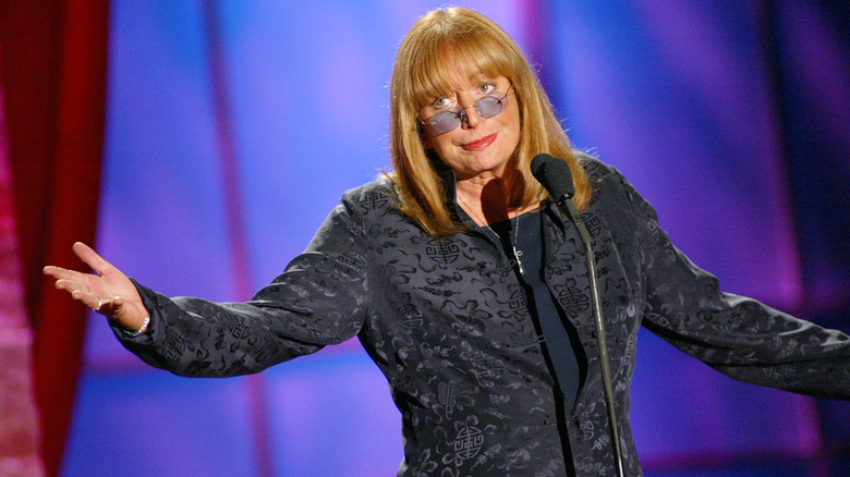 Penny Marshall at a microphone, smirking