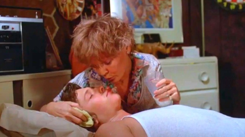 Susan Tyrell holding a glass and a sleeping Jimmy McNichol