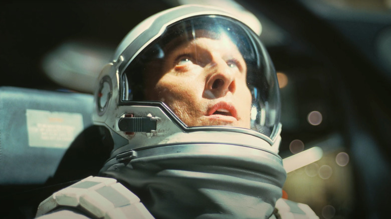 Matthew McConaughey as Cooper, dressed in a space suit, looks up at a bright light in Interstellar