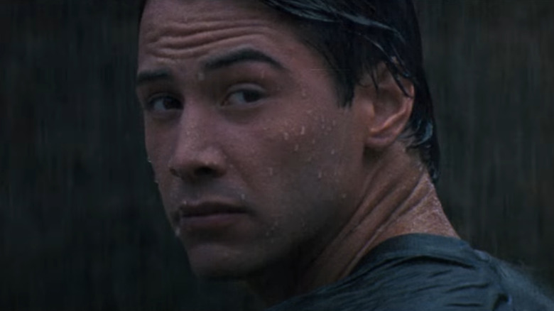 Keanu Reeves as Johnny Utah looks over his shoulder in the rain.