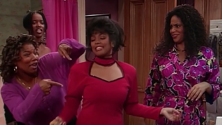 Living Single's Regine posing while Khadijah points at her and Max and Synclaire look on