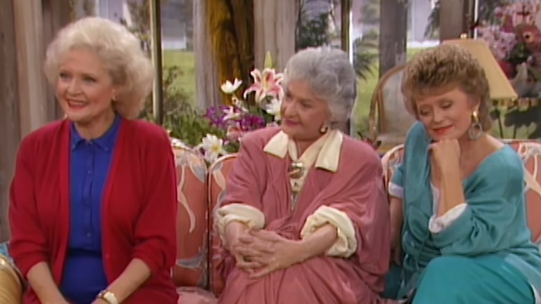 The Golden Girls' Rose, Dorothy, and Blanche sitting in a couch and smiling