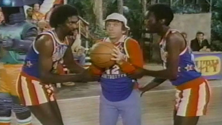 The Harlem Globetrotters help Bob Denver as Gilligan make a free throw in The Harlem Globetrotters on Gilligan's Island