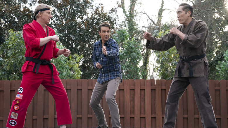 Ralph Macchio's Daniel LaRusso refereeing a fight between William Zabka's Johnny Lawrence and Yuji Okumoto's Chozen Toguchi on Cobra Kai