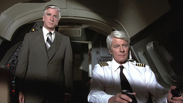 Leslie Nielsen as Dr. Rumack and Peter Graves as Captain Oveur in the cockpit of Flight 209 in Airplane!