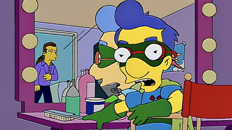 Milhouse sits at his dressing room mirror and speaks to a director seen in the doorway in The Simpsons