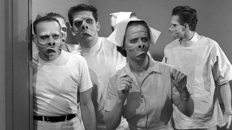 The pig-like hospital staff stand looking at something off-screen in The Twilight Zone episode 