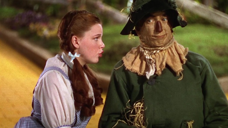 Dorothy talking to the Scarecrow next to the yellow-brick road