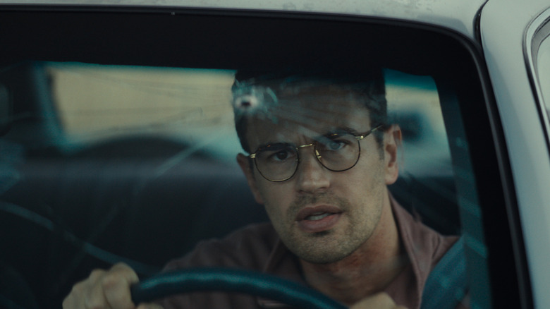 Theo James as Hal staring through a bullet hole in his car windshield in The Monkey