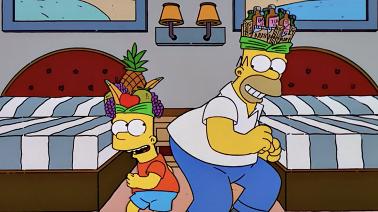 Bart and Homer dance together wearing hats made of fruit and beer bottles in The Simpsons