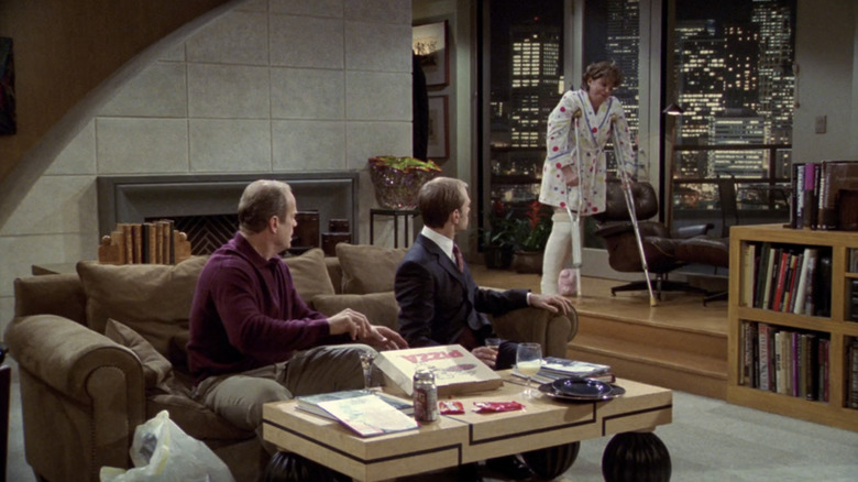 Ann Hodges hobbles into Frasier's living room on crutches as Frasier and Niles watch from the couch