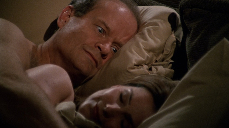 Frasier looks shocked and concerned as he lays next to Roz in bed