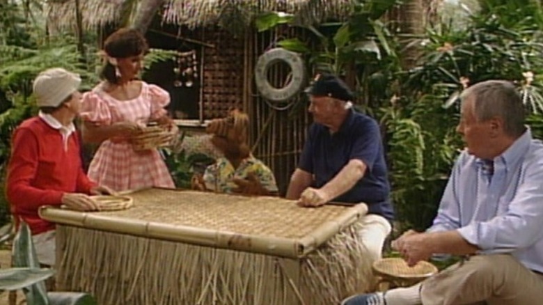 Gilligan, Mary Ann, Alf, o capitão e o professor se reuniram em torno de uma mesa