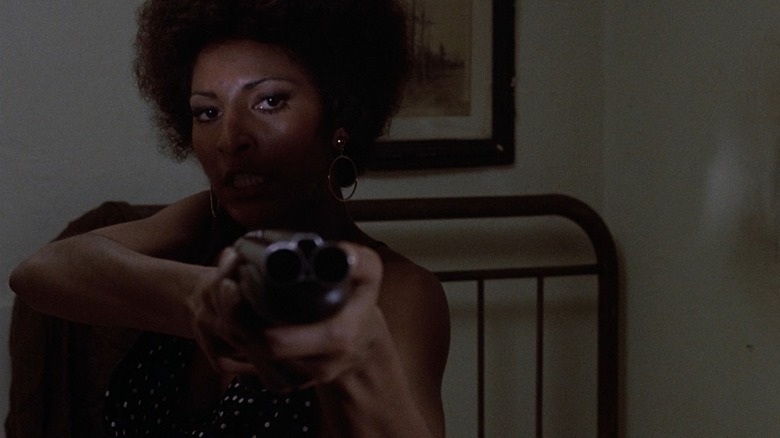 Pam Grier aiming a sawed-off shotgun