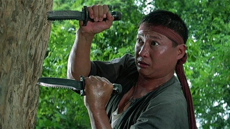 Sammo Hung climbing a tree with two knives