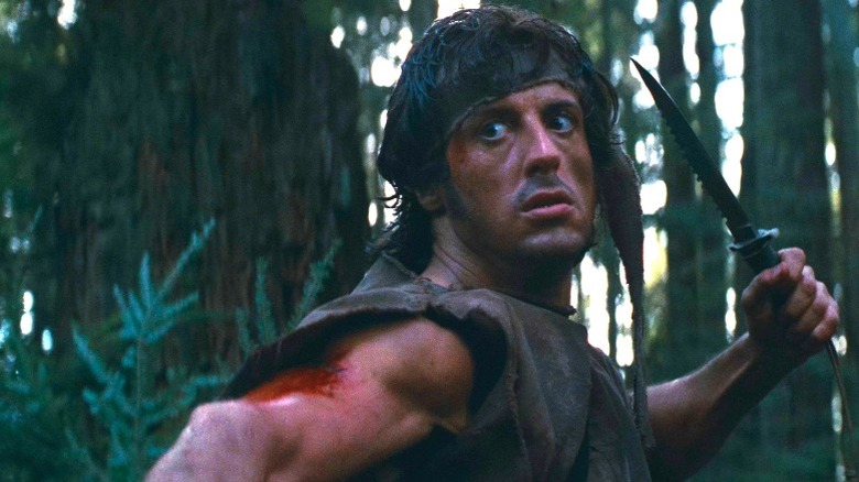 Sylvester Stallone on the run in the woods, knife in hand