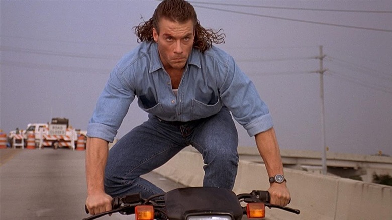 Jean-Claude Van Damme standing on a moving motorcycle