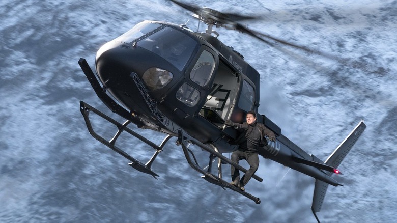 Tom Cruise hanging onto the side of a helicopter