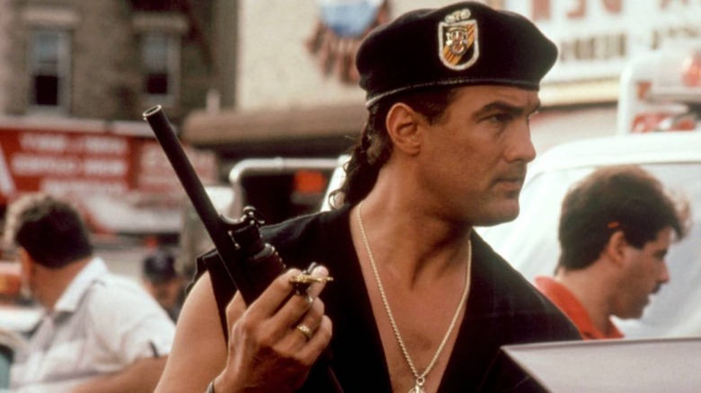 Steven Seagal holding a shotgun and car keys