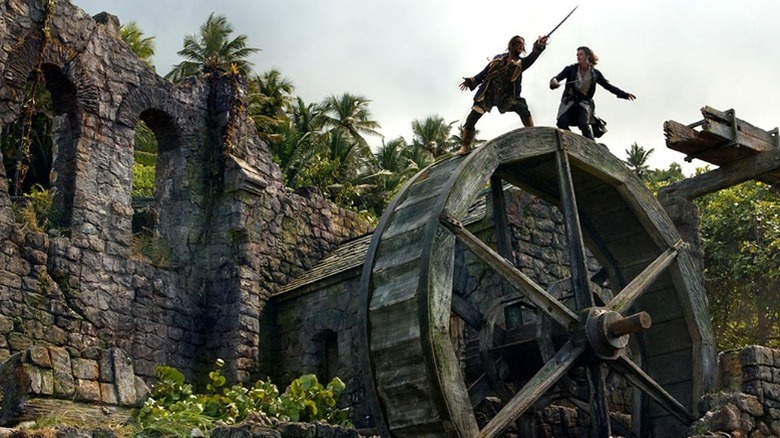 Orlando Bloom sword-fighting a pirate atop a rolling water wheel