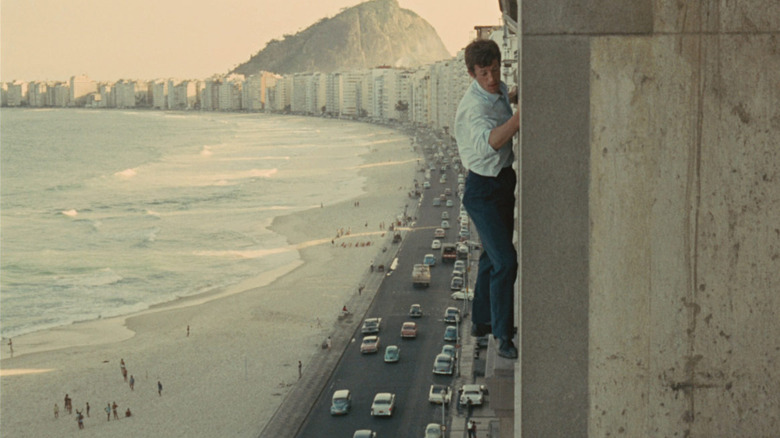 Jean-Paul Belmondo hugging a window sill high above a Rio street