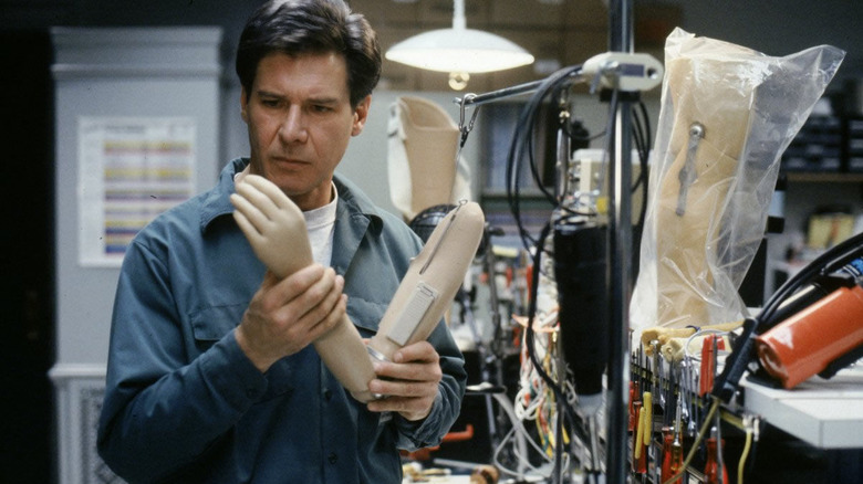 Harrison Ford studying a prosthetic arm