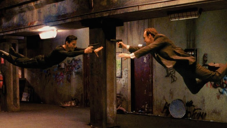 Keanu Reeves diving at Hugo Weaving, guns drawn