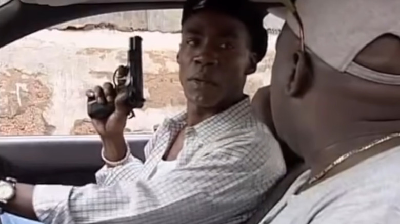 Paul Campbell in his squad car, holding a pistol