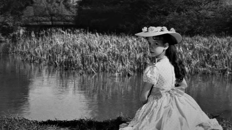  Girl sits by lake in The Innocents