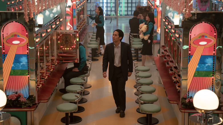 Baek Solomon (Jin Ha) Walks Through a Pachinko Parlor in Pachinko