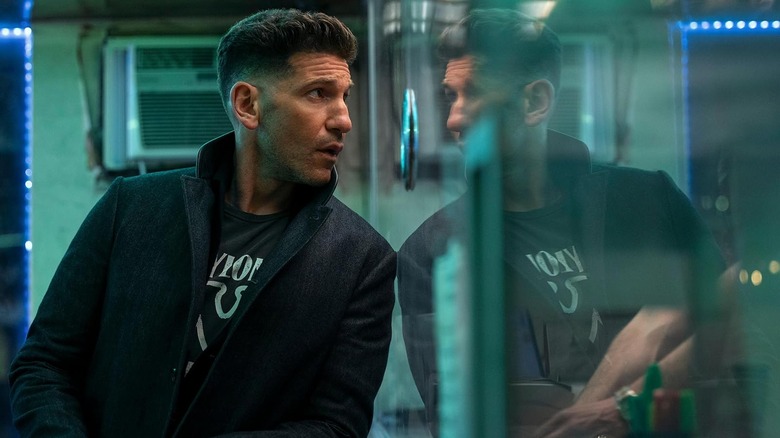 Jon Bernthal as Braxton leaning against a glass panel in The Accountant 2