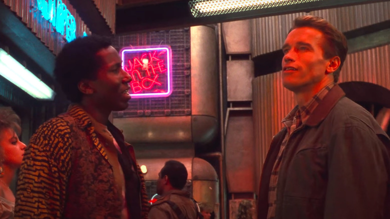 Mel Johnson Jr. and Arnold Schwarzenegger talking in neon alley