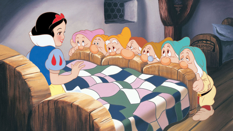 Snow White sitting in bed with dwarfs looking at her