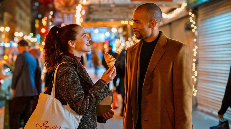 Rachel holding a pastry and smiling at Ethan on the street in Something From Tiffany's