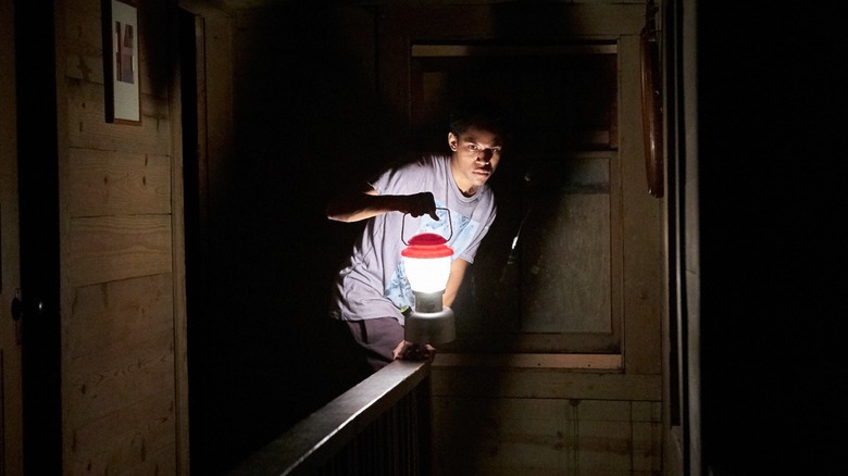 Travis holds up a lantern in the dark in It Comes At Night