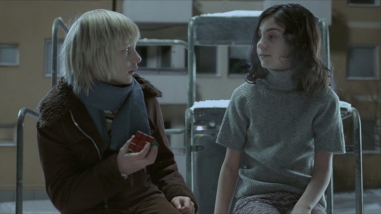 Oskar and Eli sit on a jungle gym in Let the Right One In