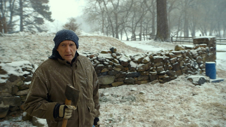 Pop Pop holds an axe in the snow in The Visit